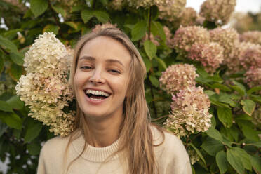 Happy young woman near flowering plants - VPIF09016