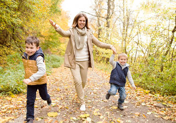 Schöne Mutter mit ihren beiden Söhnen in warmer Kleidung auf einem Spaziergang draußen in der bunten Herbstnatur. - HPIF35559