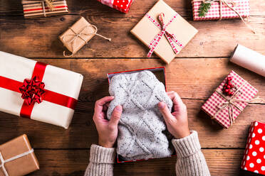 Man holding Christmas present laid on a wooden table background - HPIF35653