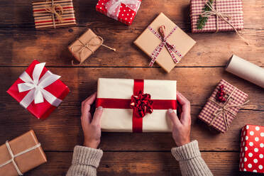 Mann hält Weihnachtsgeschenke auf einem Holztisch Hintergrund gelegt - HPIF35662