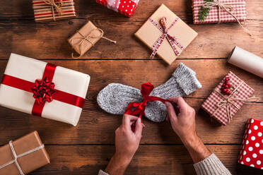 Man unwrapping Christmas present laid on a wooden table background - HPIF35663