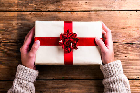 Mann hält Weihnachtsgeschenk auf einem Holztisch Hintergrund gelegt - HPIF35665