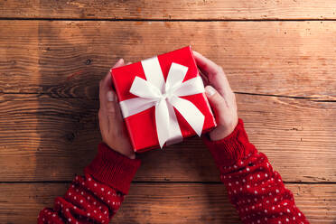 Man holding Christmas present laid on a wooden table background - HPIF35668