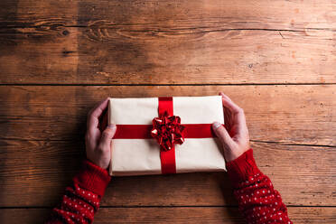 Man holding Christmas present laid on a wooden table background - HPIF35669