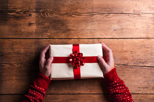 Mann hält Weihnachtsgeschenk auf einem Holztisch Hintergrund gelegt - HPIF35669