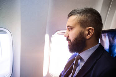 Young handsome businessman sitting inside an airplane - HPIF35749