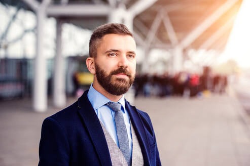 Hipster-Geschäftsmann im Anzug wartet am Flughafen, sonniger Tag - HPIF35762