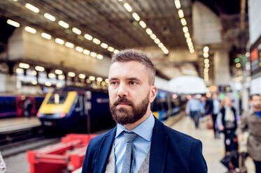 Nahaufnahme eines Hipster-Geschäftsmannes, der auf dem Bahnsteig wartet - HPIF35770