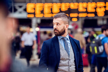 Hipster Geschäftsmann im Anzug wartet auf dem überfüllten Londoner Bahnhof - HPIF35780