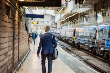 Geschäftsmann im Anzug zu Fuß auf dem Bahnsteig, Rückansicht, Blick von hinten - HPIF35796