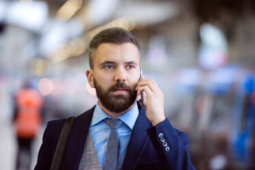 Hipster-Geschäftsmann mit Smartphone, der einen Anruf tätigt, auf dem Bahnhofsvorplatz - HPIF35797