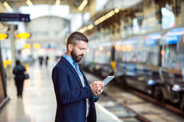 Hipster businessman with tablet, waiting at the train station platform - HPIF35801