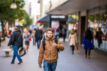 Young hipster man in brown winter jacket walking in the streets of London - HPIF35808