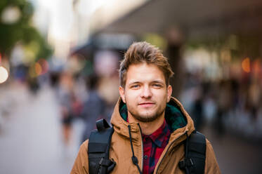 Nahaufnahme eines jungen Hipster-Mannes in brauner Winterjacke, der durch die Straßen von London läuft - HPIF35809