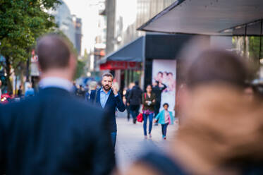 Hipster-Manager, der ein Smartphone in der Hand hält und einen Anruf tätigt, auf einer Straße in London - HPIF35820