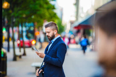 Handsome young manager with smartphone in London - HPIF35823