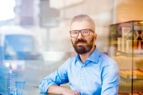 Hipster-Manager sitzt in Café am Fenster mit einem Glas Wasser, Straße Reflexion - HPIF35848