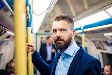 Junger gut aussehender Geschäftsmann mit Smartphone in der U-Bahn - HPIF35878