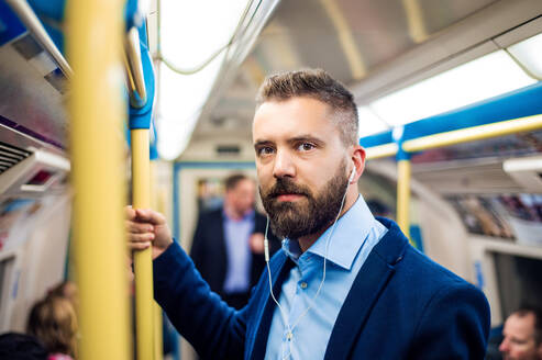 Junger gut aussehender Geschäftsmann mit Smartphone in der U-Bahn - HPIF35878