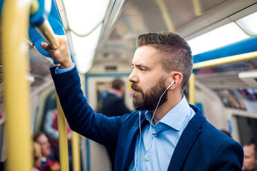 Junger gut aussehender Geschäftsmann mit Smartphone in der U-Bahn - HPIF35879