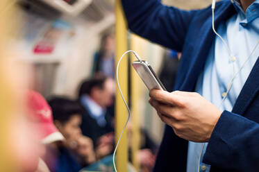 Young handsome businessman with smartphone in subway - HPIF35882