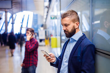 Young handsome businessman with smart phone in subway - HPIF35889