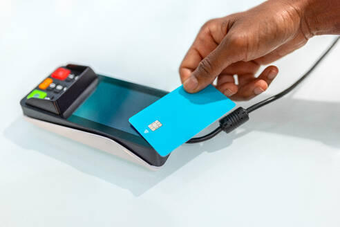 Crop Hand von anonymen weiblichen Kunden zieht Kreditkarte durch Zahlungsterminal auf weißen Tisch in Apotheke speichern - ADSF50359