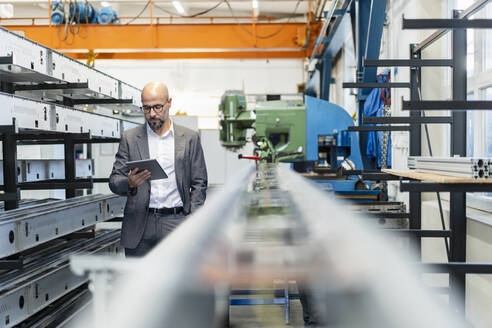 Businessman using tablet PC near machinery in factory - DIGF21019