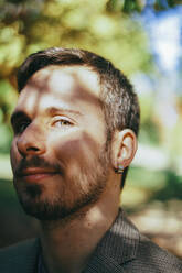 Smiling young man with beard and sunlight on face - SVCF00422