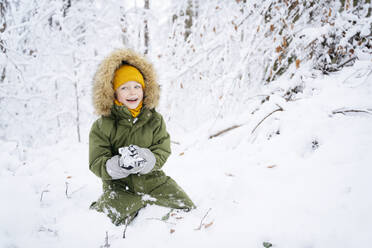 Happy boy making snowball at winter forest - NJAF00712