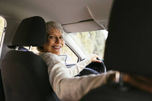 Smiling woman holding steering wheel in car - EBSF04288