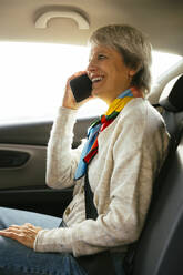 Glückliche Frau sitzt im Auto und spricht mit ihrem Smartphone - EBSF04291