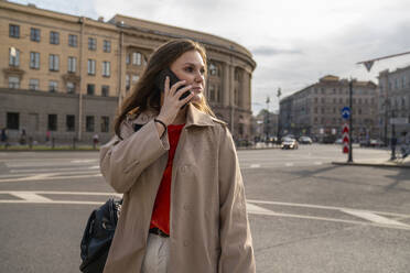 Frau, die vor einem Gebäude mit einem Mobiltelefon spricht - VPIF09033