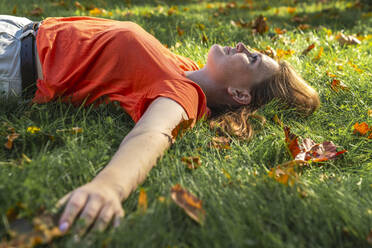 Thoughtful young woman relaxing on grass at park - VPIF09078