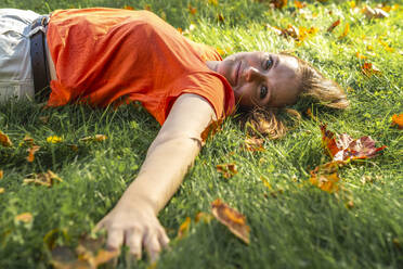 Lächelnde junge Frau entspannt sich auf einer Wiese im Park - VPIF09079