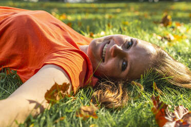 Happy young woman relaxing on grass at park - VPIF09080