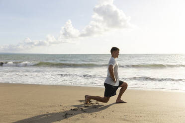 Man doing stretching exercise near sea at beach - STF00006