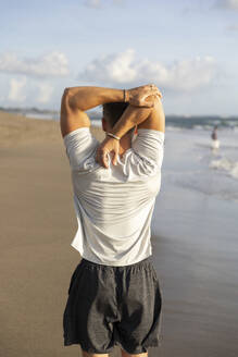 Man doing stretching exercise at beach - STF00008