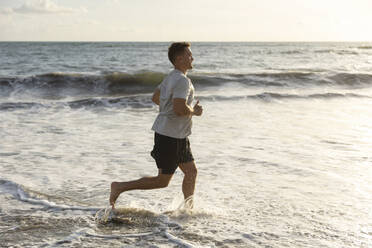 Man running in sea water at beach - STF00015
