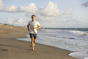 Young man jogging near sea at beach - STF00016