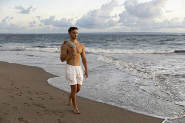 Shirtless man walking near sea at beach - STF00029
