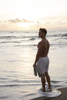 Shirtless man standing in sea water at beach - STF00030