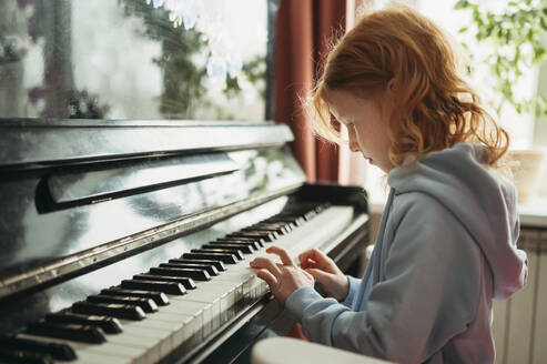 Redhead girl playing piano at home - ANAF02551