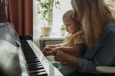 Mother teaching daughter to play piano at home - ANAF02555