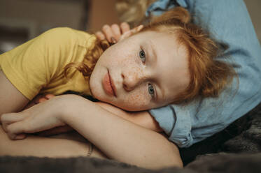 Contemplative daughter lying on mother's lap at home - ANAF02567