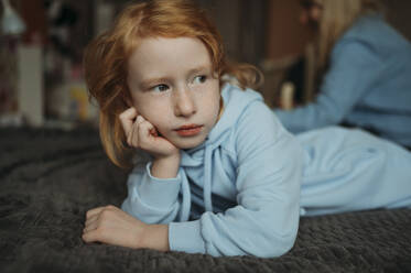 Contemplative girl lying on bed at home - ANAF02569