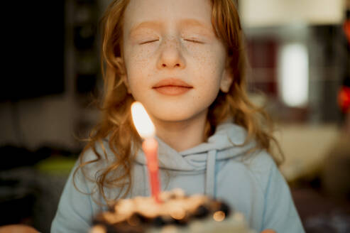 Girl holding birthday cake with candle at home - ANAF02572