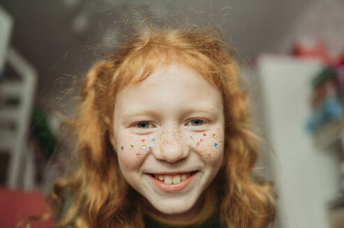 Smiling girl with sequins on face at home - ANAF02583