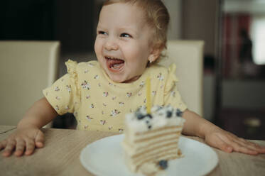 Happy girl celebrating birthday with cake at table - ANAF02589