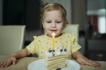 Smiling girl celebrating birthday with cake at table - ANAF02590